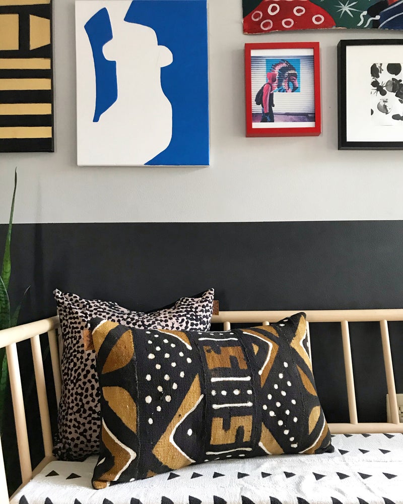 Brown, black, and white mudcloth pillows with geometric designs styled on Scandinavian bench. Modern pillows made in USA, designed in Mali. Seen here with African art.