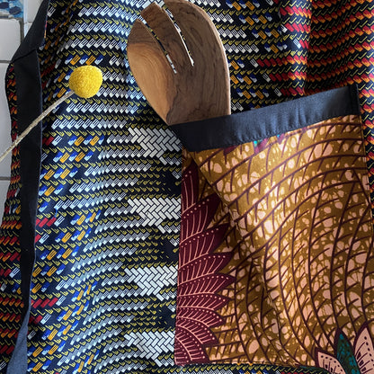 Detail of Handcrafted African wax print apron made in Uganda. Perfect for housewarming and wedding gitfs. Excellent for entertaining guests during the holidays, Thankgiving, Christmas, and more. Shown with olivewood salad server.