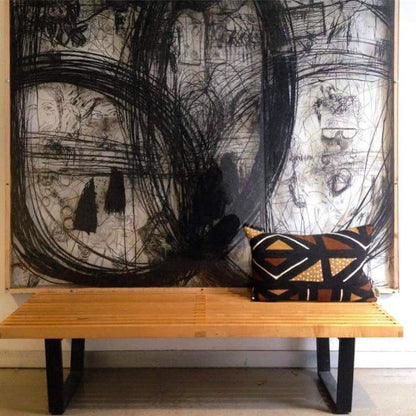 Brown, black, and white mudcloth pillows with geometric designs styled on Scandinavian bench. Modern pillows made in USA, designed in Mali. Seen here with African art.